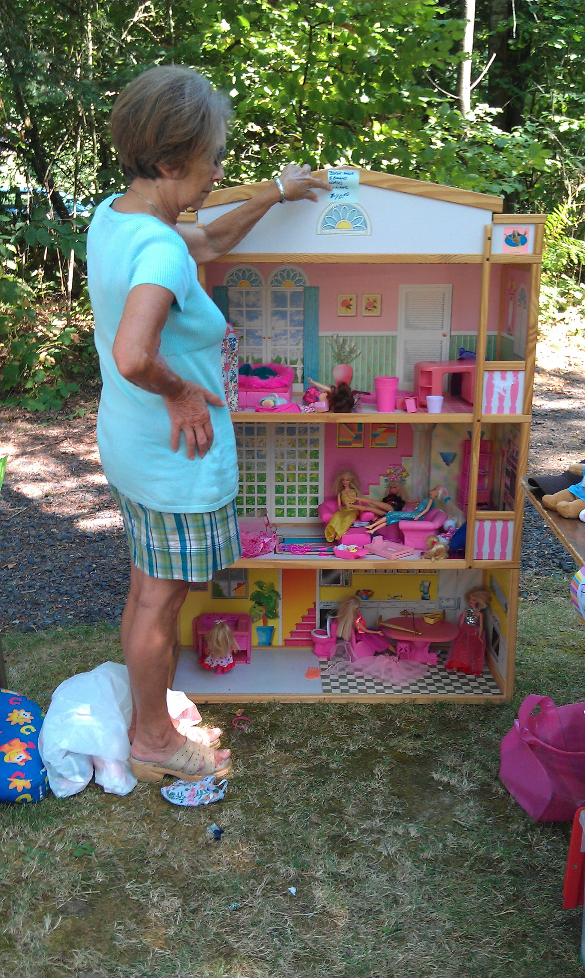 Wanda standing beside a three-storey dolls' house filled with furniture and figures